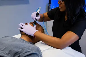 Provider steadies a client's jaw while guiding the treatment wand upward during a HydraFacial in Preston