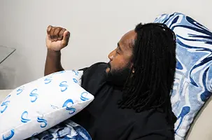 Client raises a fist mid session, propped on a pillow during his Deep Ellum IV injection session