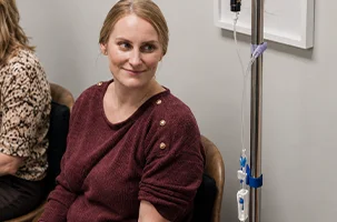 Infusion bag hangs beside a smiling woman midway through her IV drip in Lakewood
