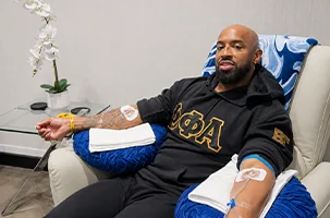 Both arms lined and taped, a relaxed client waits out his IV drip North Dallas appointment
