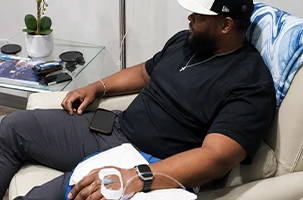 Client settles back on the couch after a vitamin injection in Downtown Dallas, arm bandaged and resting